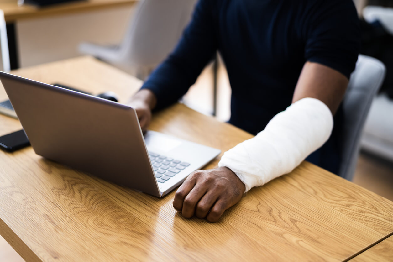 Person with injured arm on computer