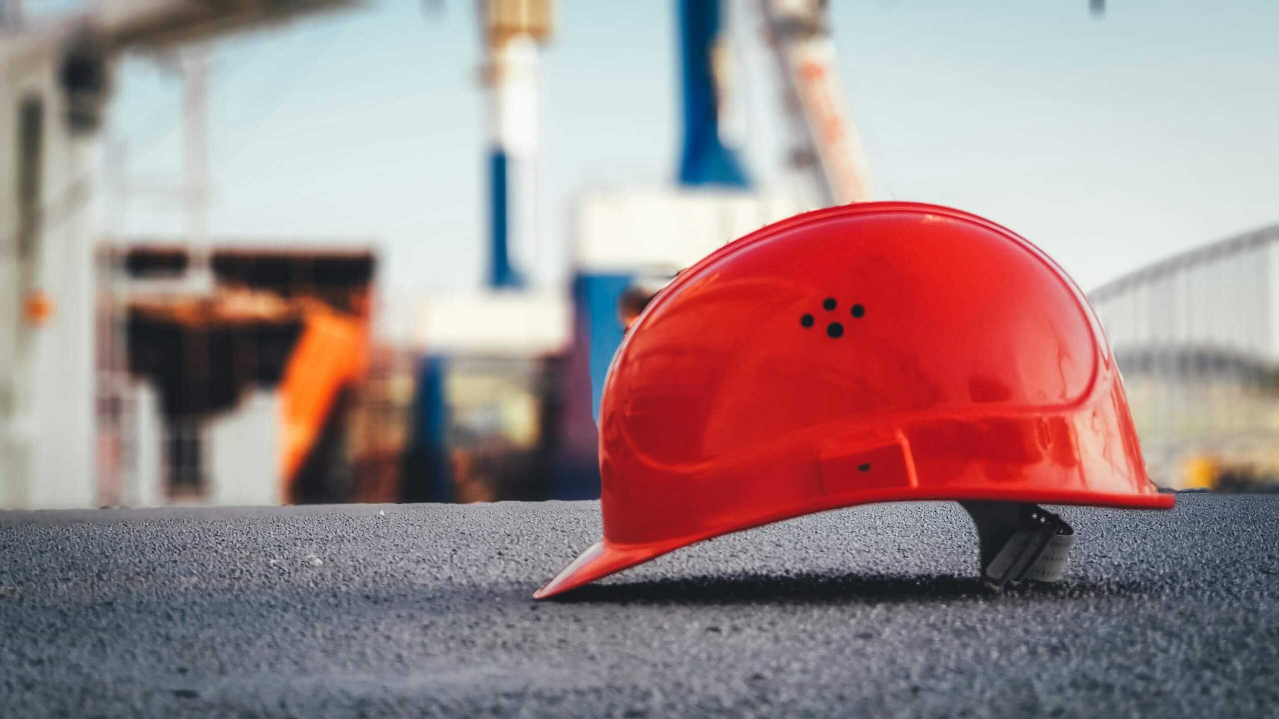 Casco de construcción rojo tirado en el pavimento